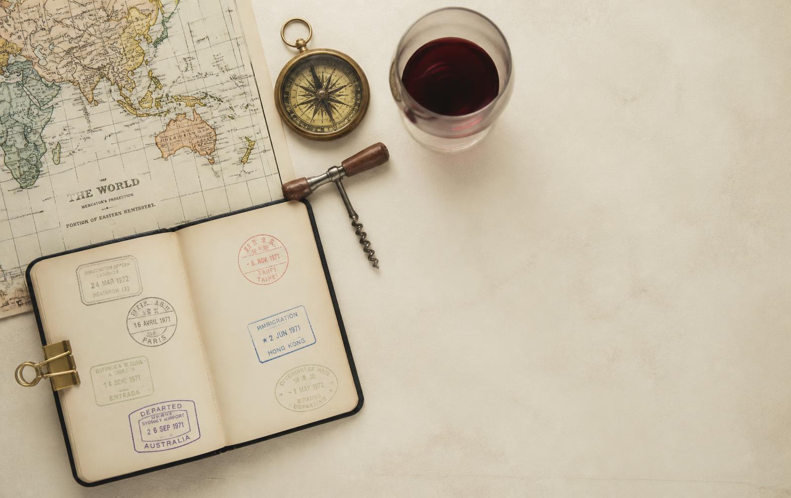 Carnet de voyage tamponné, carte du monde, boussole et verre de vin
